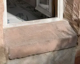 Faded sandstone windowsill with historic graffiti, sunlight illuminating iris-patterned mosaics inside, soft garden shadows outside