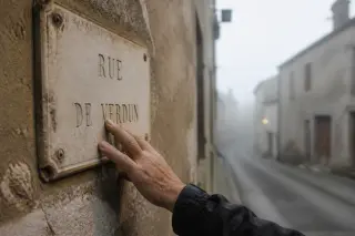 Weathered hand gently touching a stone street plaque on an old facade in a quiet, misty lane.